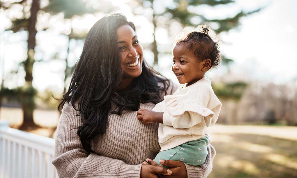 woman smiles while holding her daughter